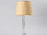 a clear glass lamp with a beige shade on top of it