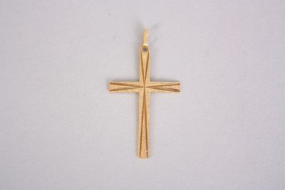 gros plan d'une croix en or sur une surface blanche