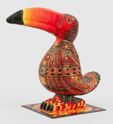 un toucan orange et noir posé sur un socle en bois