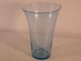 un vase en verre bleu posé sur une surface blanche