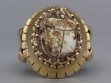 an image of a gold ring with a scarabus stone in the center