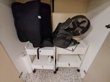 une valise et un ventilateur dans un coin d'un placard