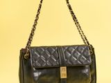 un sac en cuir noir muni d'une bandoulière en chaîne et d'un fermoir doré