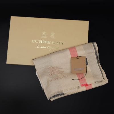 the burbery scarf is next to a gift box on a table