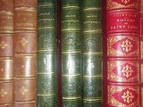 several old books are lined up in a row on a shelf