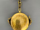 an antique brass bell with a bow hanging from it ' s side