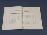 un livre ouvert sur lequel figure une liste, posé sur une table
