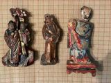 trois figurines représentant des personnes sont disposées sur une nappe à carreaux