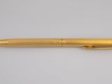 a gold pen sitting on top of a white surface
