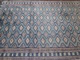 une photo d'un tapis bleu et marron posé au sol
