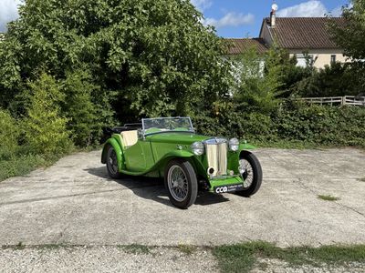 une voiture verte garée sur un parking à côté d'une maison