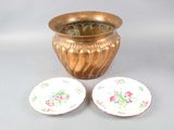 un vase en or et deux assiettes posées l'une à côté de l'autre