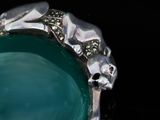 a silver ring with a green stone in it
