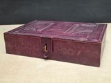 an old purple book sitting on top of a table next to a black wall