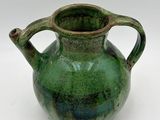 a green vase that is sitting on a white surface