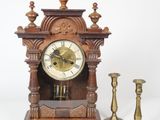 a small wooden clock and two candles on a white background