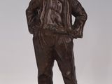 bronze statue of a boy with a hat and jacket standing on a base