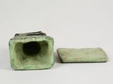 two pieces of green pottery sitting next to each other on a white surface