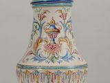 a white vase with a bird on it sitting on a table