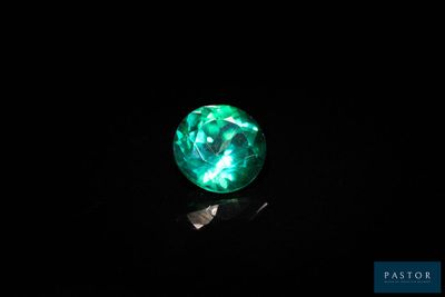 a close up of a green glass ball on a black surface