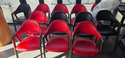 rows of red and black chairs sit in a room with a large window
