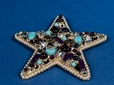 star brooch with multi colored stones and beads on a blue background