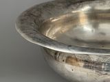 a silver bowl on a stand on a white surface