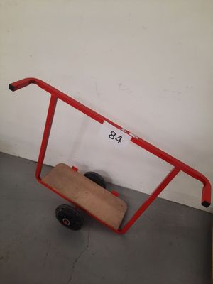 un chariot rouge sur lequel est posée une planche en bois, dans une pièce