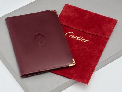 un gros plan sur un portefeuille et une pochette rouge posés sur une surface blanche