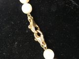 a close up of a necklace with pearls on a mannequin