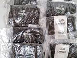 a lot of black shirts in plastic bags on a table