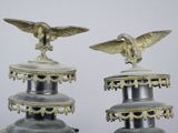 two metal vases with a bird on top of them