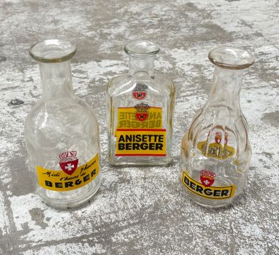 trois bouteilles en verre vides posées sur une surface en béton