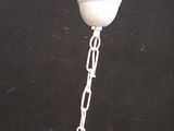 a bird that is sitting on a chain attached to a light fixture