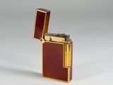 an image of a gold and red lighter sitting on top of a white surface