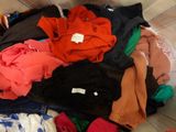 a pile of clothes that is sitting on a bed