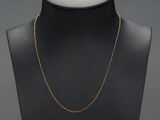 a gold necklace on a mannequin neck with a black background