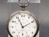 a silver pocket watch sitting on a clear display case