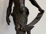 statue en bronze représentant un homme tenant un marteau et un banc