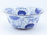 blue and white bowl with flowers and leaves on it on a white surface