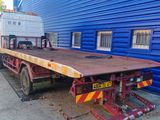 the flatbed trailer is parked in front of a blue building
