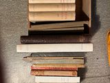 a pile of books on the floor next to a baseball bat