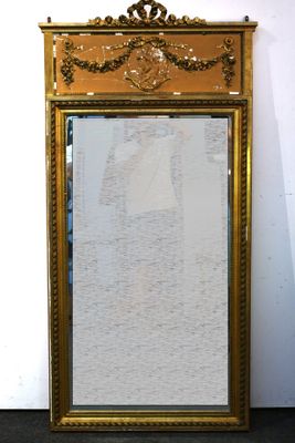 un miroir à cadre doré posé par terre devant un mur blanc