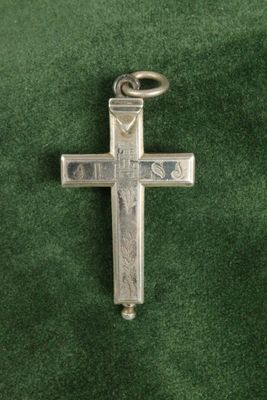 une croix en argent sur un tissu vert, avec un porte-clés au milieu