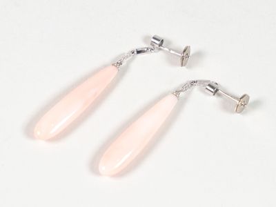 une paire de boucles d'oreilles pendantes en verre rose sur fond blanc