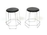 two black stools sitting next to each other on a white surface