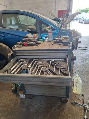 une voiture garée dans un garage, avec des outils dessus