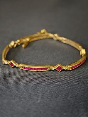 un gros plan sur un bracelet en or orné de pierres roses