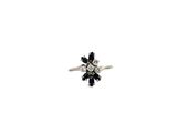 une image représentant une bague ornée de pierres noires et blanches sur fond blanc