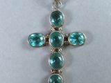 un pendentif en forme de croix orné de pierres vertes sur fond blanc